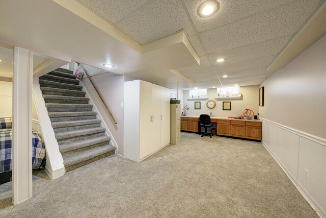 below grade area with light carpet, stairs, a drop ceiling, and recessed lighting