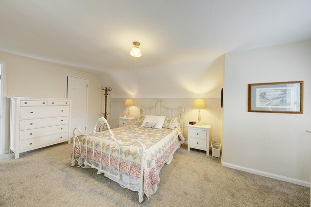 bedroom with baseboards, vaulted ceiling, and light colored carpet