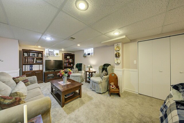 living room with light carpet, visible vents, a wainscoted wall, a paneled ceiling, and recessed lighting