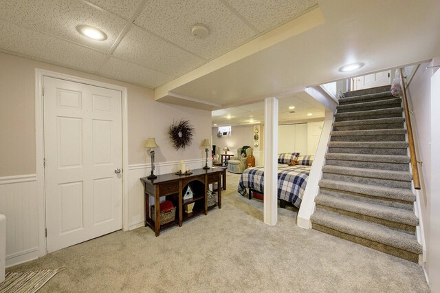 interior space with stairway, wainscoting, a paneled ceiling, and light colored carpet