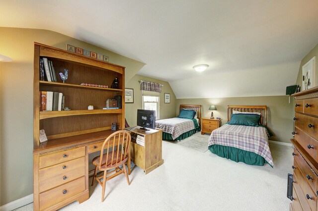 bedroom with vaulted ceiling, built in desk, baseboards, and light colored carpet