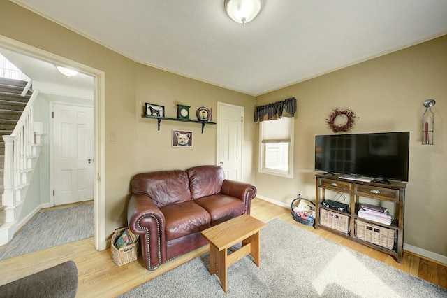 living room with stairs, baseboards, and wood finished floors