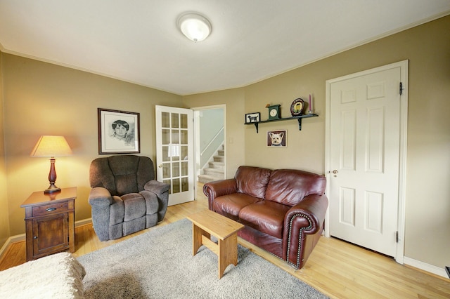 living area with french doors, stairway, baseboards, and wood finished floors