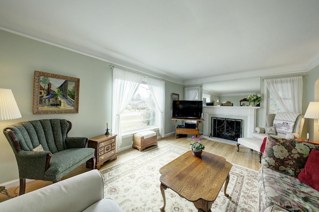 living area with crown molding, a fireplace, baseboards, and light wood-style floors