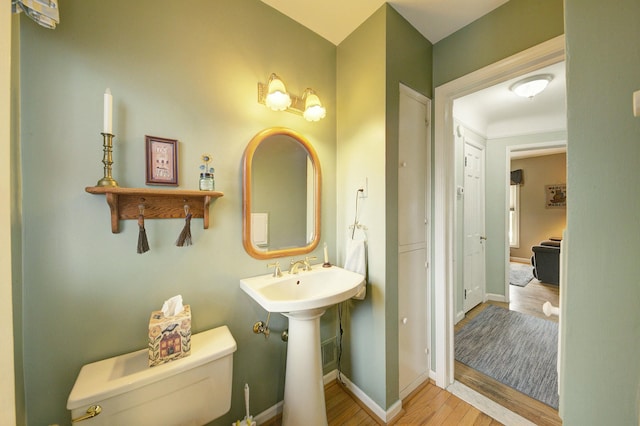 bathroom with baseboards, toilet, and wood finished floors