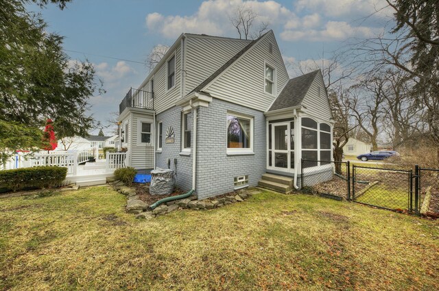 rear view of property with brick siding, a lawn, a sunroom, a gate, and fence