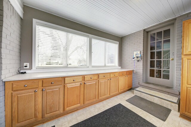 interior space with light floors, light countertops, and brick wall