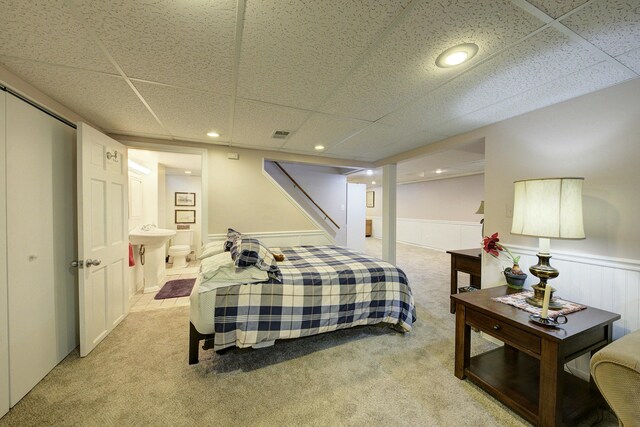 bedroom with wainscoting, a drop ceiling, and light colored carpet