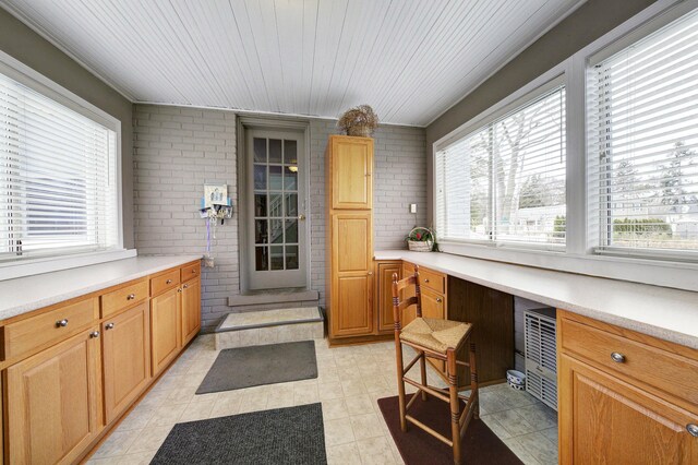 kitchen featuring brick wall, light countertops, and built in study area