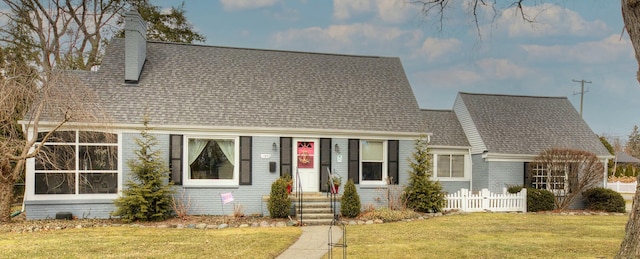 new england style home featuring a shingled roof, a chimney, fence, a front lawn, and brick siding