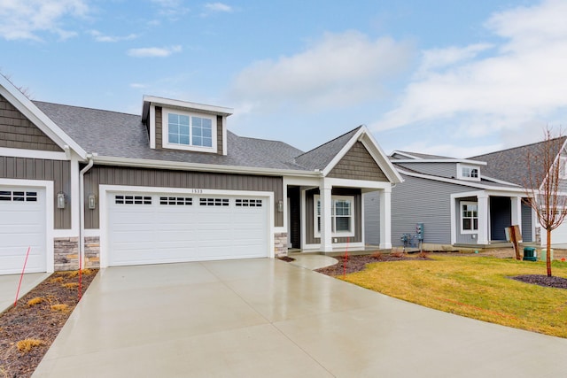 view of front of house featuring an attached garage, driveway, roof with shingles, board and batten siding, and a front yard