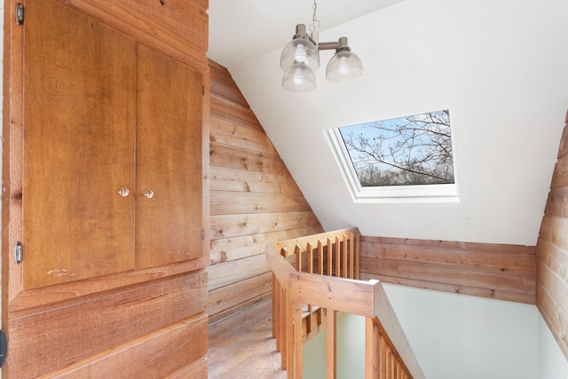 additional living space with wooden walls, an inviting chandelier, and vaulted ceiling