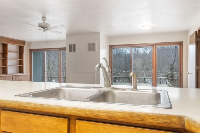 kitchen with ceiling fan, light countertops, visible vents, and a sink