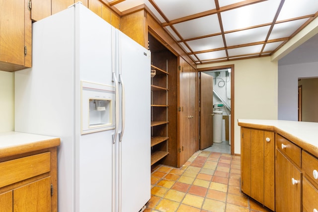 kitchen with light countertops, white refrigerator with ice dispenser, brown cabinets, and open shelves