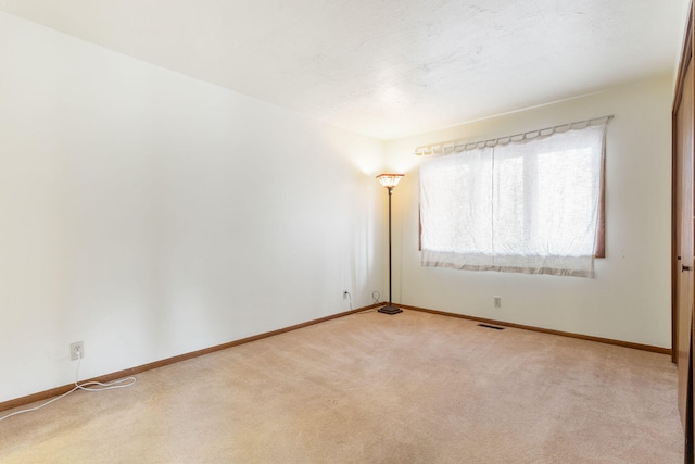 carpeted spare room with visible vents and baseboards