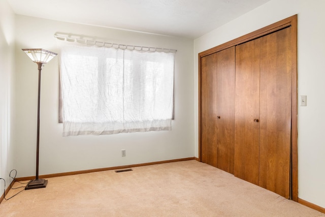 unfurnished bedroom featuring carpet, visible vents, a closet, and baseboards