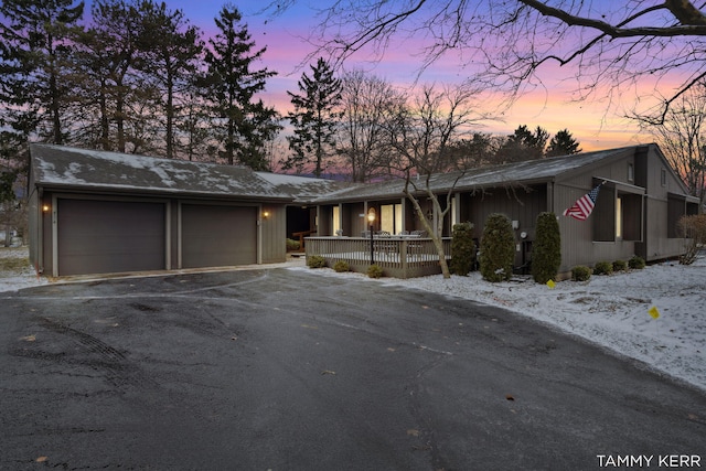 view of front of property featuring a garage, a porch, and aphalt driveway