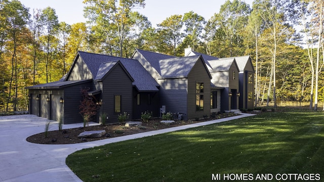 view of side of home with a garage, a shingled roof, driveway, a lawn, and a chimney