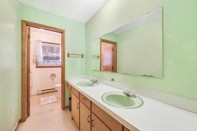 bathroom with a sink, a baseboard heating unit, toilet, and double vanity