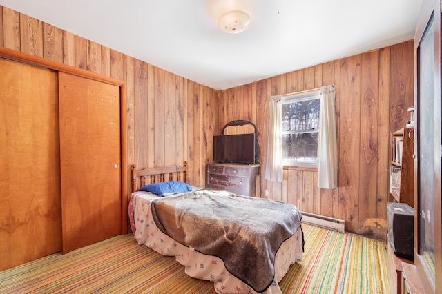 bedroom featuring a closet, wood walls, and a baseboard heating unit