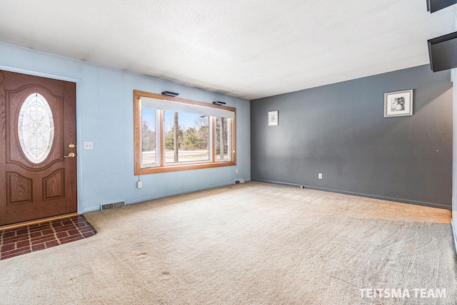 foyer featuring carpet flooring, visible vents, and a textured ceiling