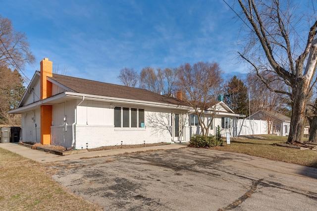 view of front facade featuring a garage, a front yard, brick siding, and a chimney