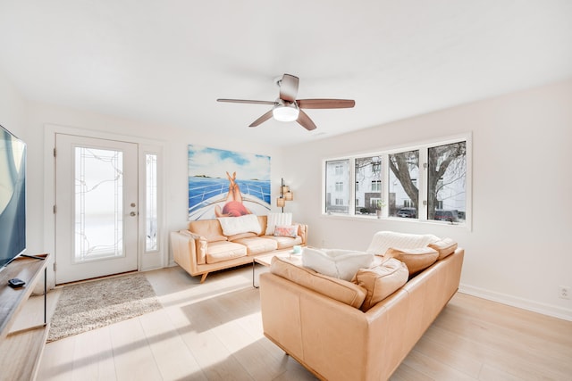 living area featuring a ceiling fan, a healthy amount of sunlight, light wood-style flooring, and baseboards