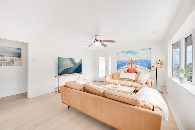 living area featuring light wood-style flooring, baseboards, and a ceiling fan