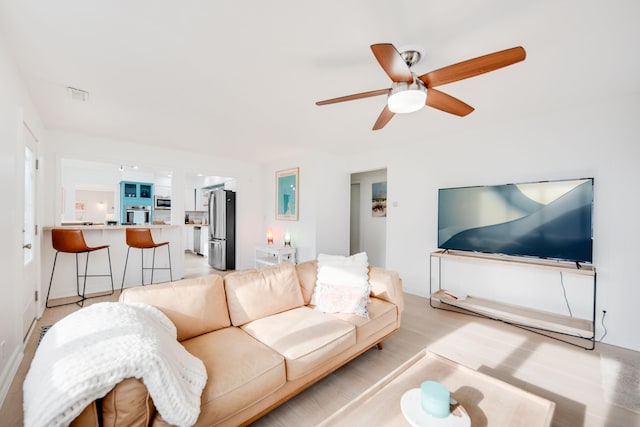 living area with light wood finished floors and a ceiling fan