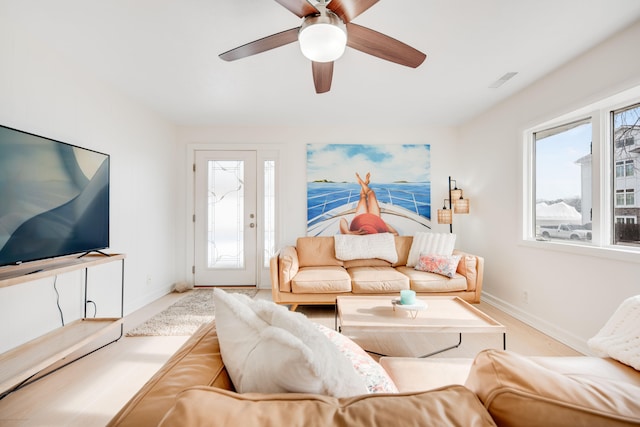 living area featuring baseboards, ceiling fan, visible vents, and a healthy amount of sunlight