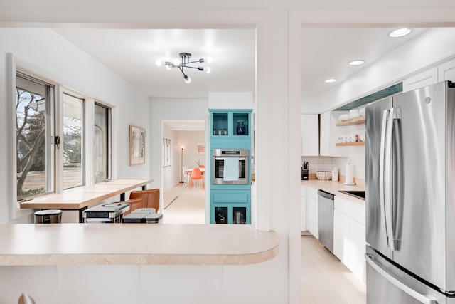 kitchen with white cabinets, light countertops, appliances with stainless steel finishes, backsplash, and open shelves