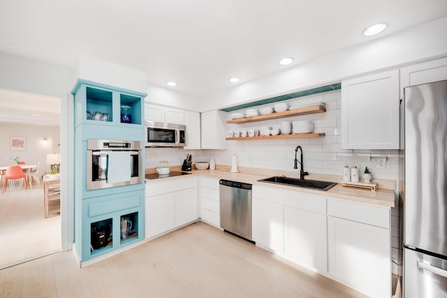 kitchen featuring open shelves, backsplash, stainless steel appliances, and a sink