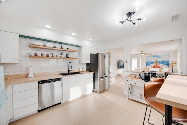 kitchen with tasteful backsplash, visible vents, appliances with stainless steel finishes, light countertops, and a sink