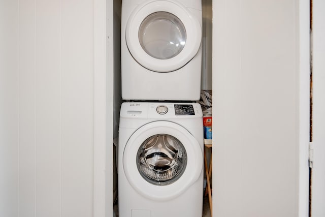 clothes washing area with stacked washer and dryer and laundry area