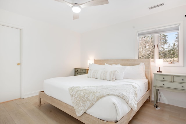 bedroom with a ceiling fan, visible vents, light wood-style flooring, and baseboards