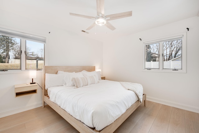 bedroom with light wood-type flooring, visible vents, baseboards, and ceiling fan