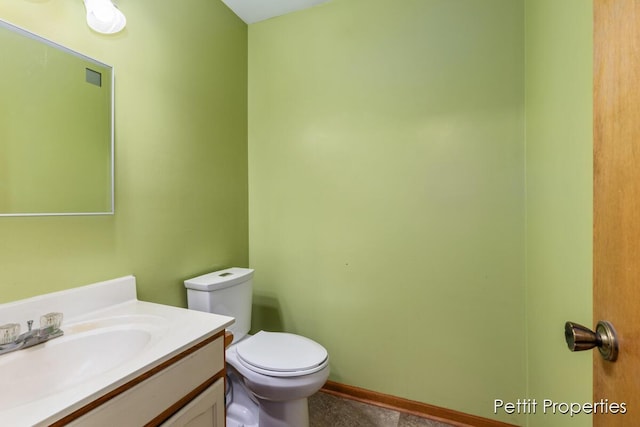 half bath featuring toilet, baseboards, and vanity