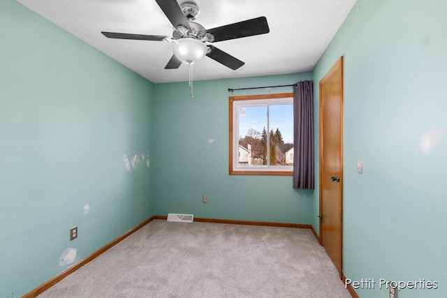 carpeted spare room with visible vents, ceiling fan, and baseboards