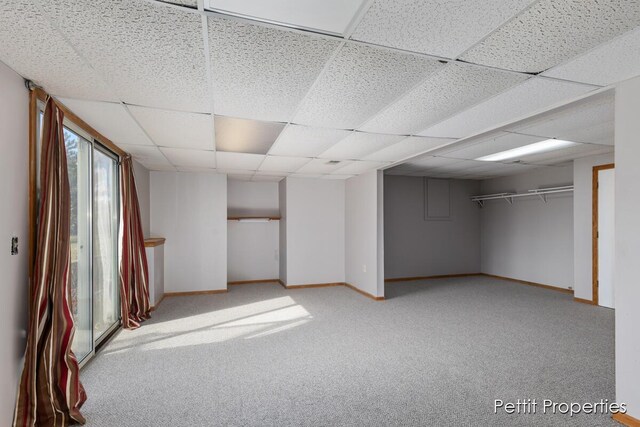 below grade area featuring a paneled ceiling, carpet flooring, and baseboards