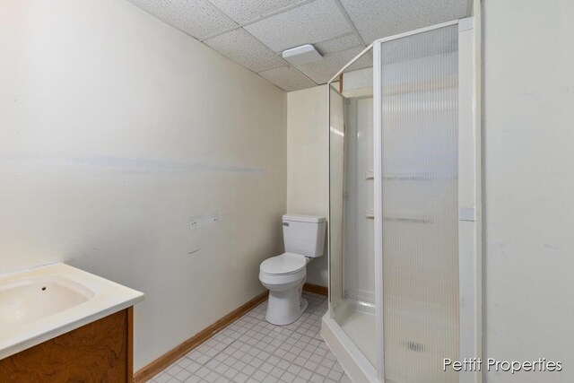 full bathroom with baseboards, toilet, vanity, a paneled ceiling, and a shower stall