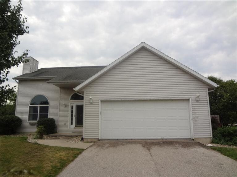 view of front of house featuring driveway, a chimney, and an attached garage