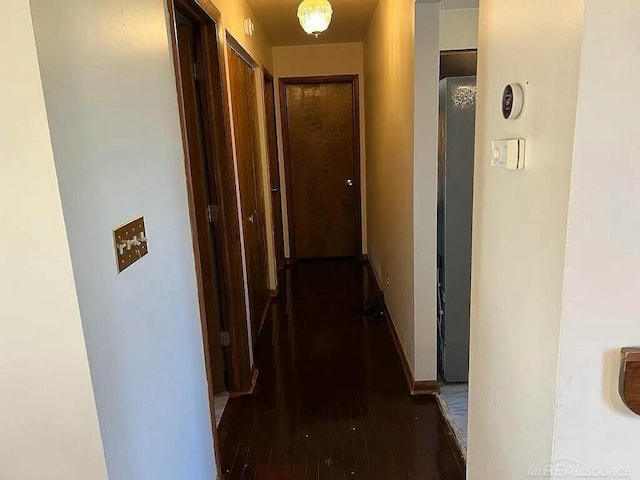 hall with baseboards and wood finished floors