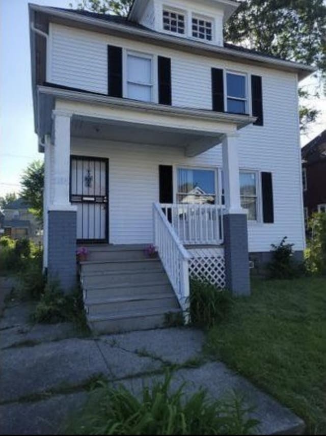 american foursquare style home with covered porch and a front yard