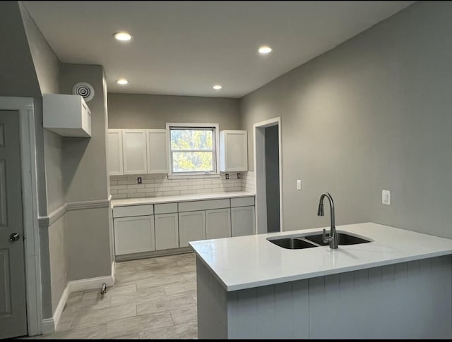 kitchen with tasteful backsplash, recessed lighting, light countertops, a sink, and a peninsula