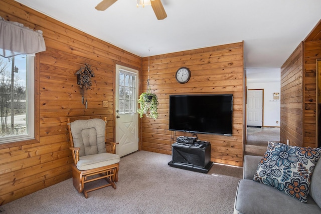 living room featuring ceiling fan, carpet floors, and wood walls