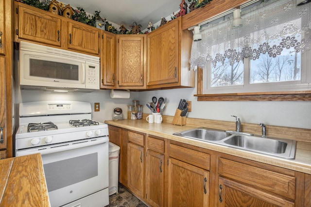 kitchen with brown cabinets, white appliances, light countertops, and a sink