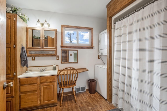 bathroom featuring stacked washer and dryer, curtained shower, visible vents, vanity, and wood finished floors