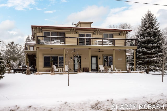 snow covered back of property featuring a balcony and ceiling fan