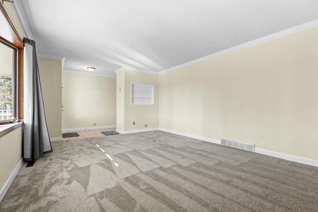 empty room featuring a textured ceiling, carpet, visible vents, and crown molding