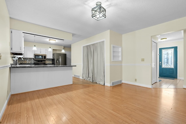 kitchen featuring appliances with stainless steel finishes, visible vents, light wood-style flooring, and white cabinetry